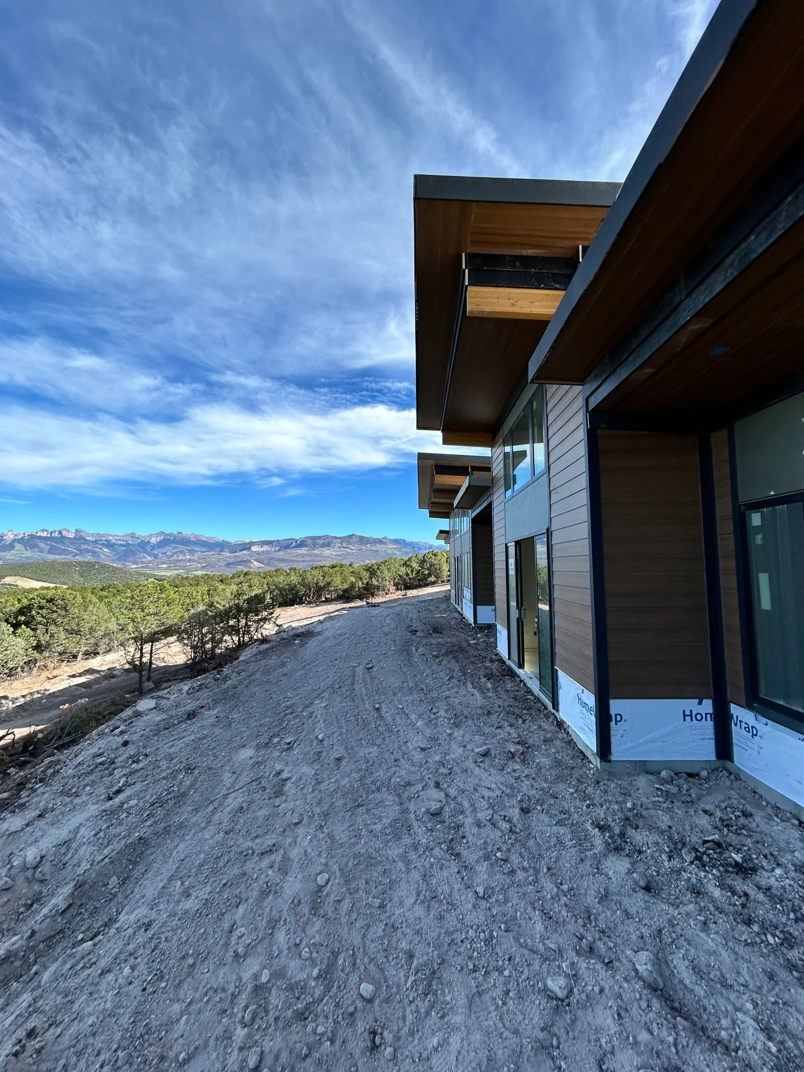 Excavated hillside with graded dirt, modern home foundation, mountain valley backdrop