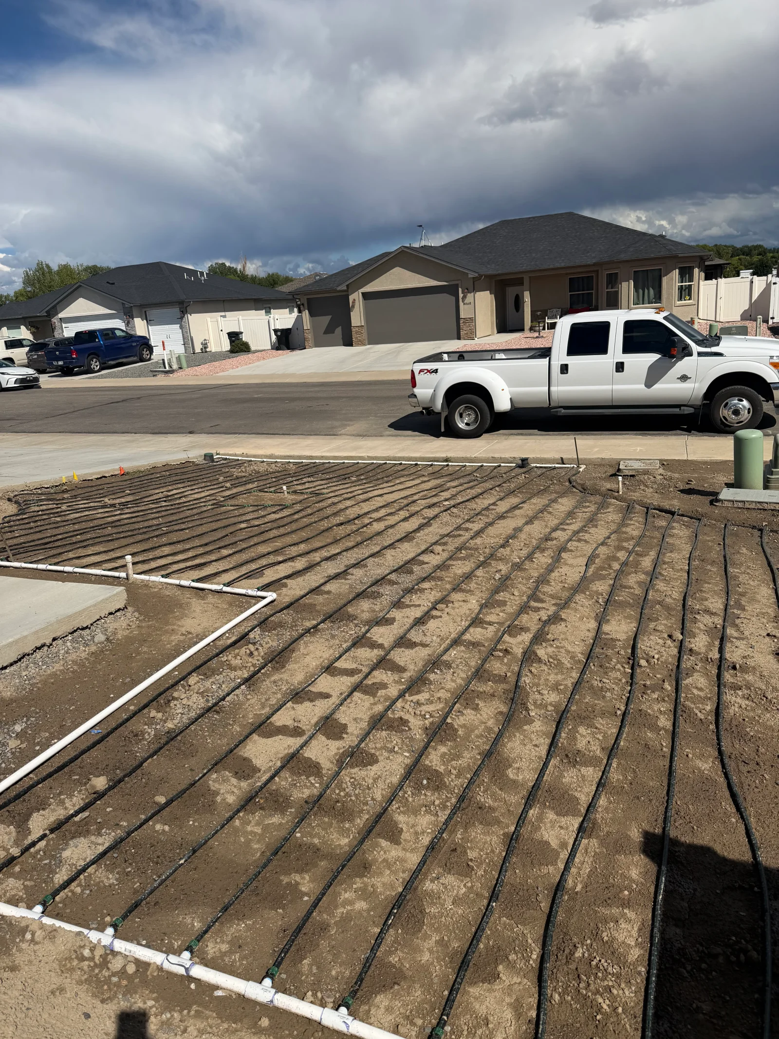 Excavated foundation site with radiant heating lines and white perimeter edging on compacted soil